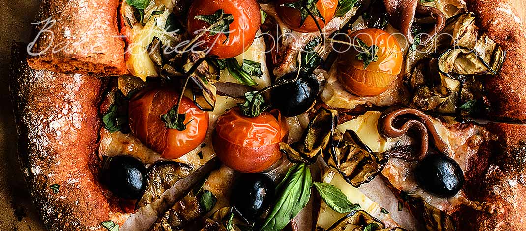 Red pepper pizza with eggplant, anchovies and black olives